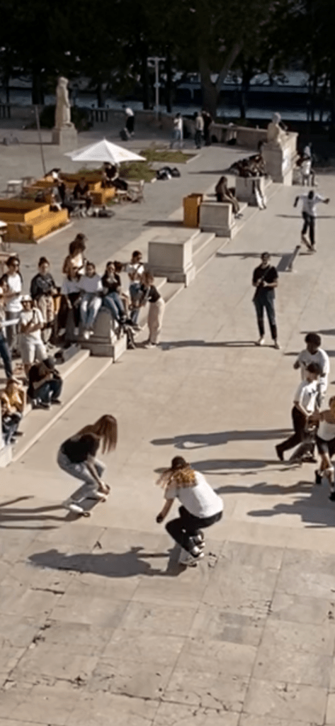 Des filles s'amusent assez sportivement à se défier par des sauts en skate sur l'esplanade basse du palais de Tokyo
