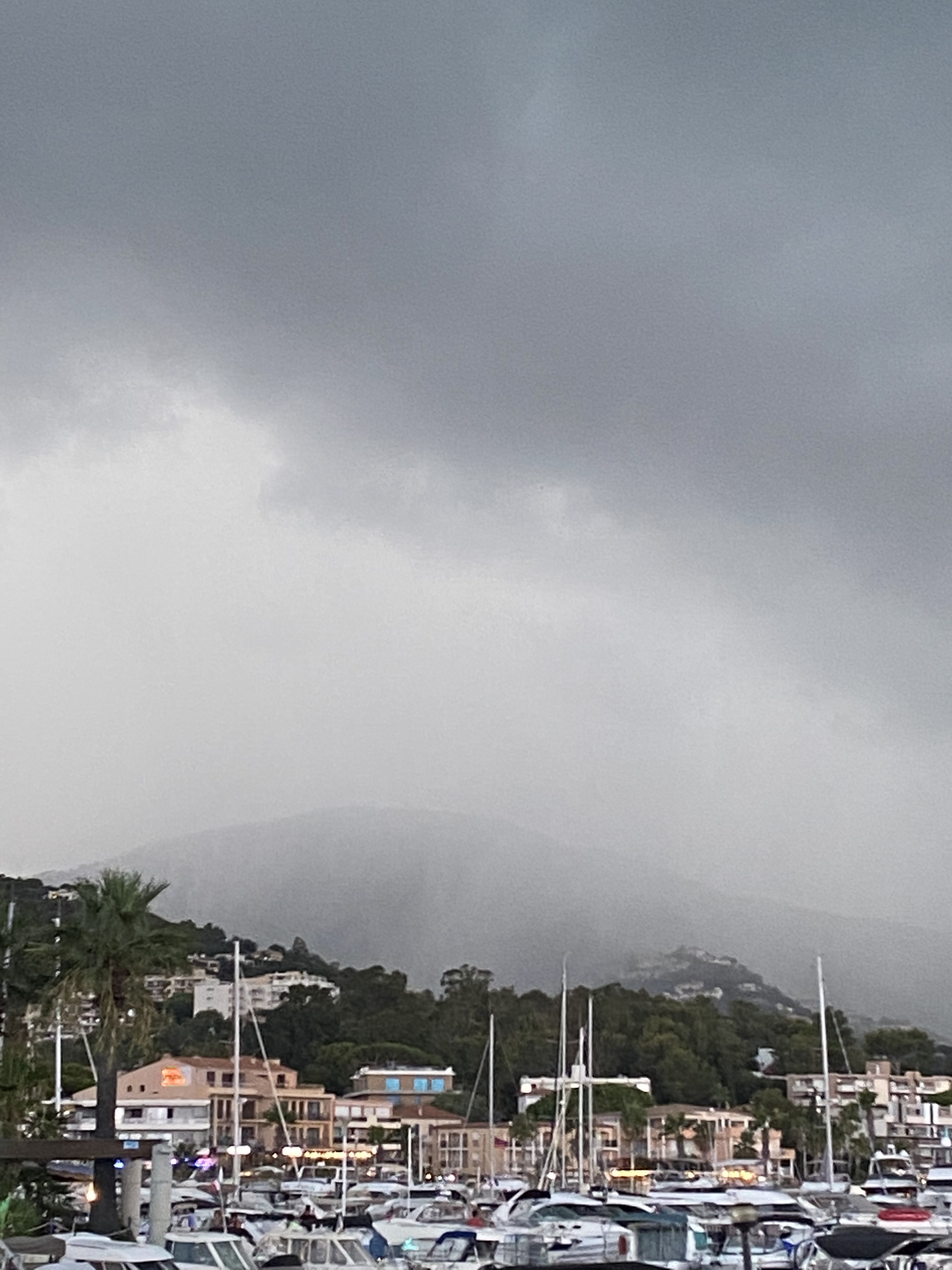 UN énorme nuage de pluie orageuse s'avance sur le bateaux bien alignés dans la marina du port de Cavalaire. Les palmiers attendent le choc