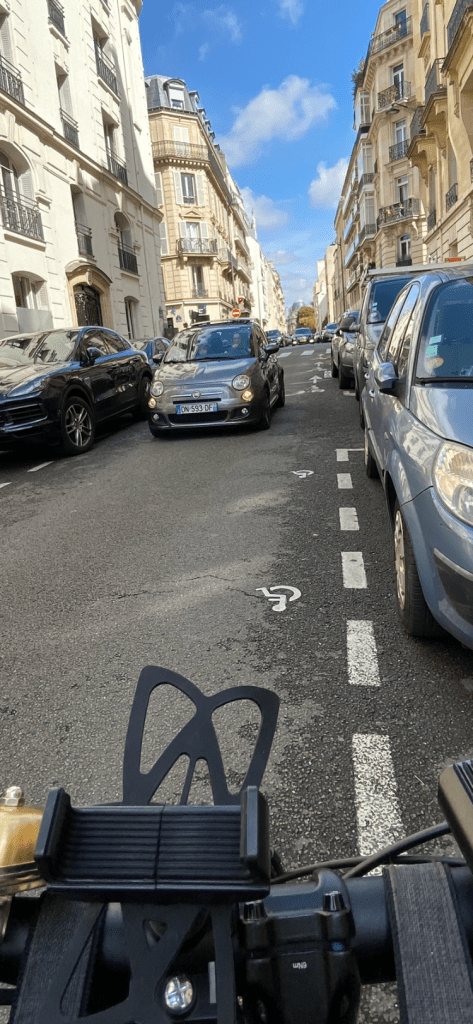 Un cycliste pédalant rue Cortambert prend en photo depuis son vélo en mouvement la voiture arrivant en face dans cette rue à sens unique. La voiture avance doucement pour ne pas risquer le choc frontal. Bravo !